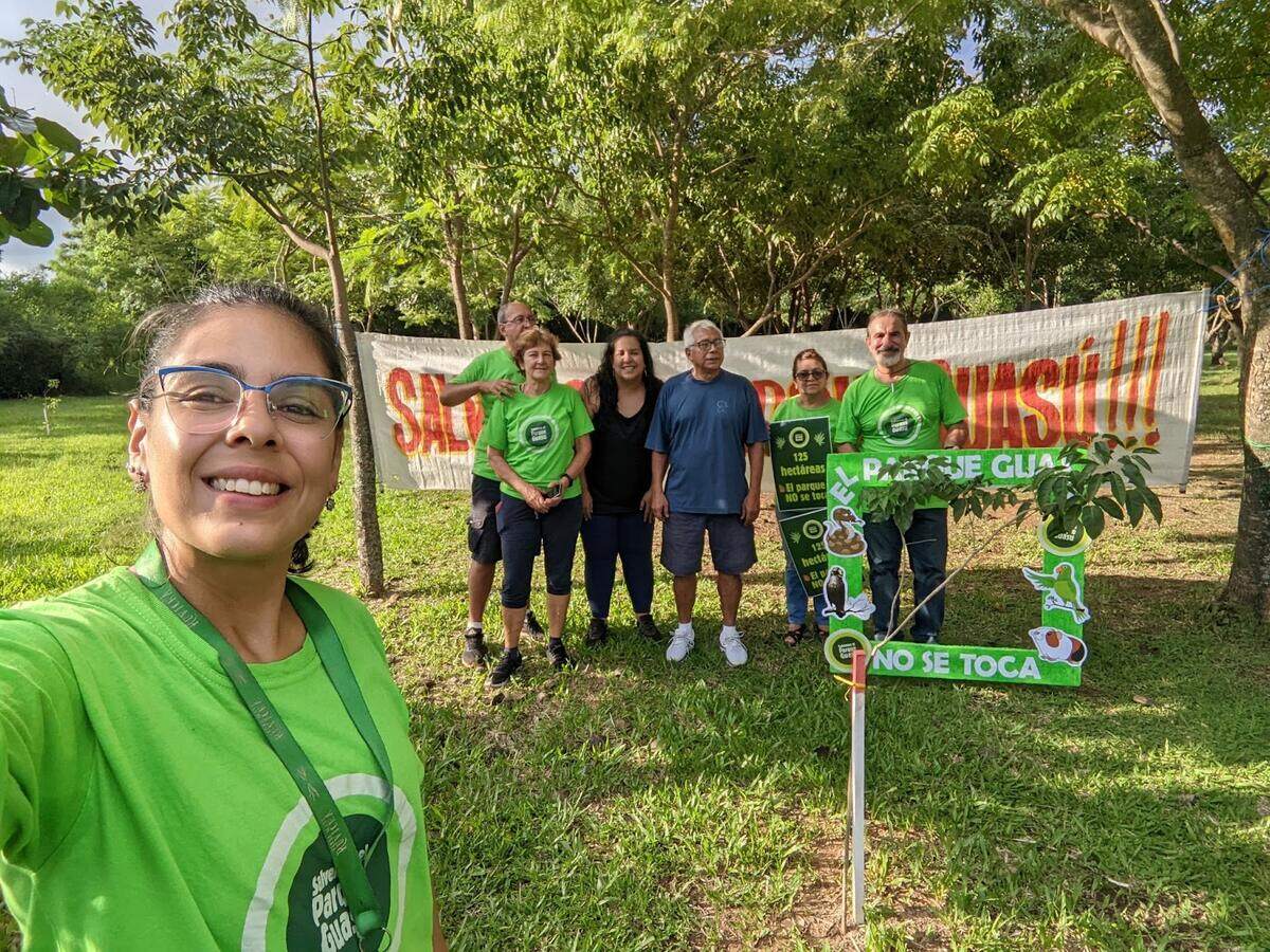 Integrantes de la agrupación en el parque, con remeras verdes y una pancarta